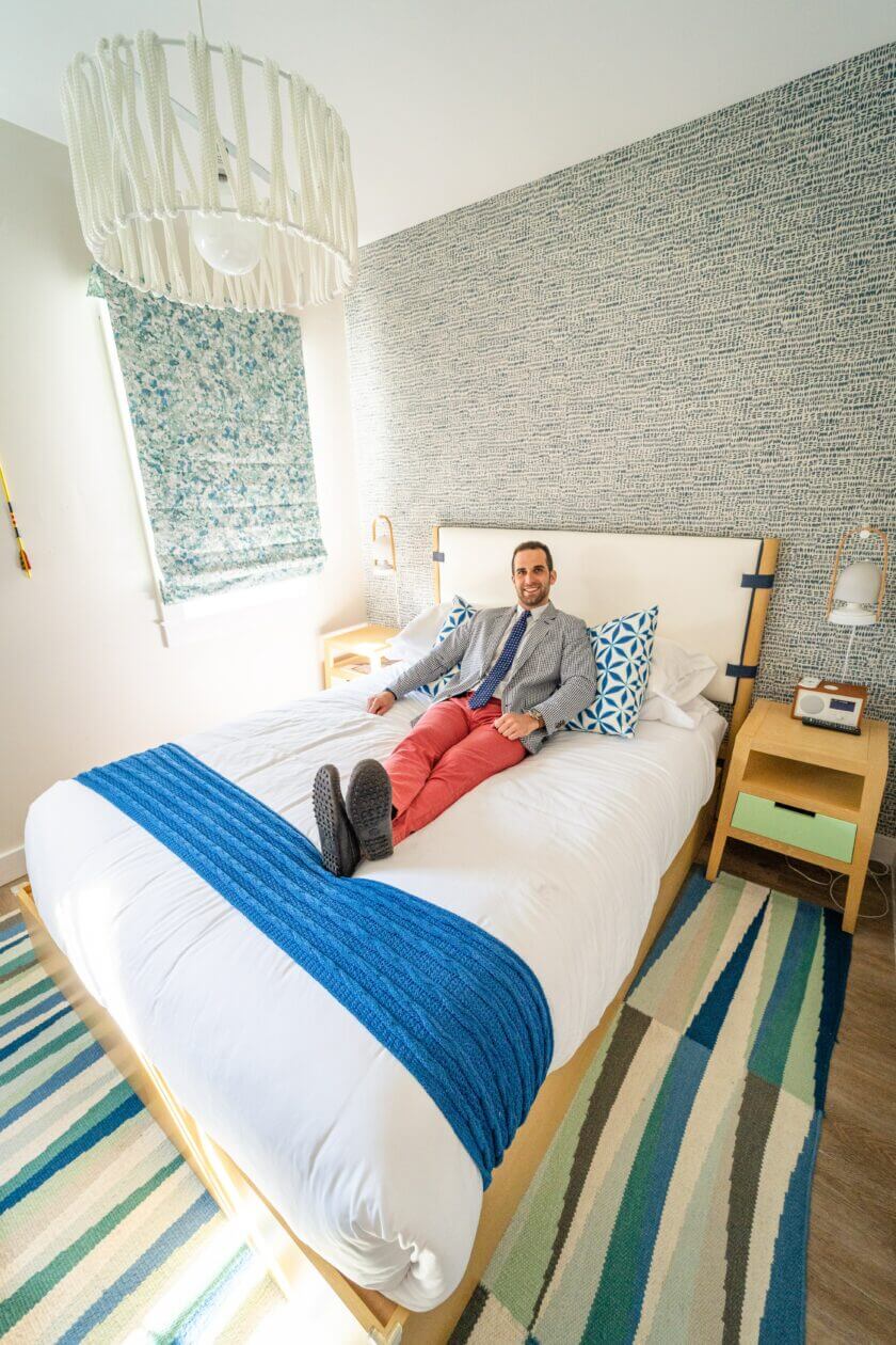 Our hotel website designs help more customers with this gentleman lying and smiling in his hotel room.