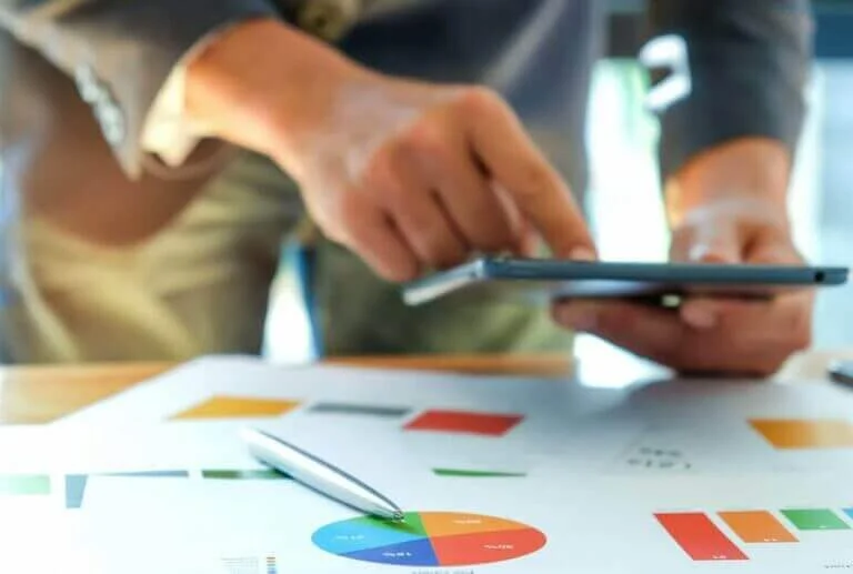 Businessmen are analyzing graphs and using tablets.