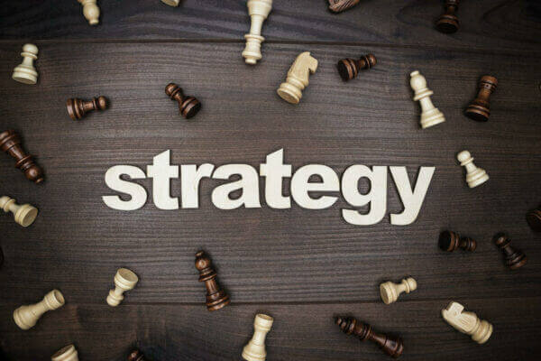 The words PCC campaign Strategy On Wooden Background with chess pieces scattered around it.