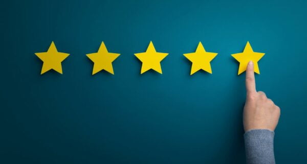 Woman hand pointing at five star SEO rating on green background