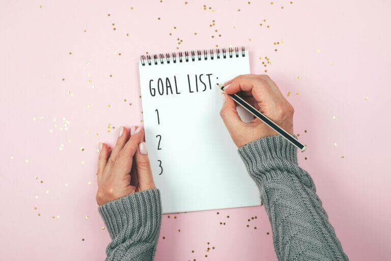 A woman creating a social media marketing plan with a pad and paper.