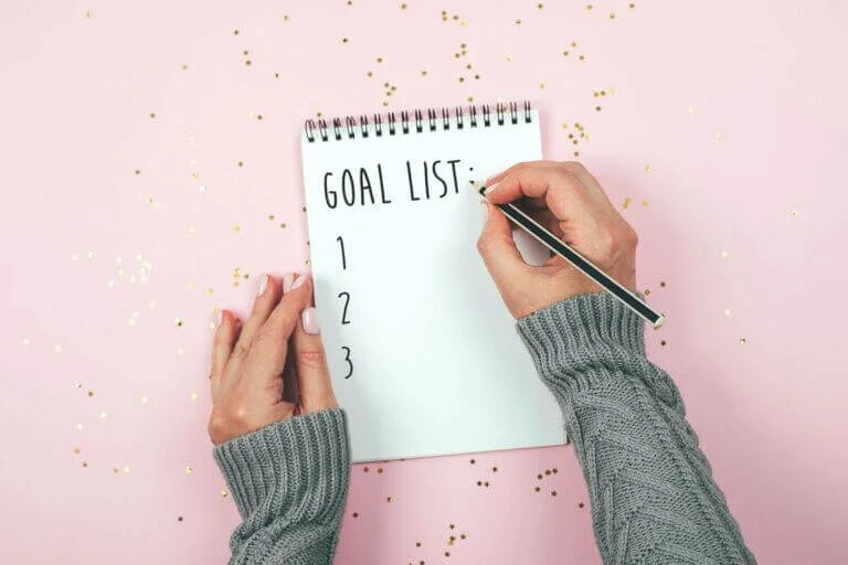 A woman creating a social media marketing plan with a pad and paper.