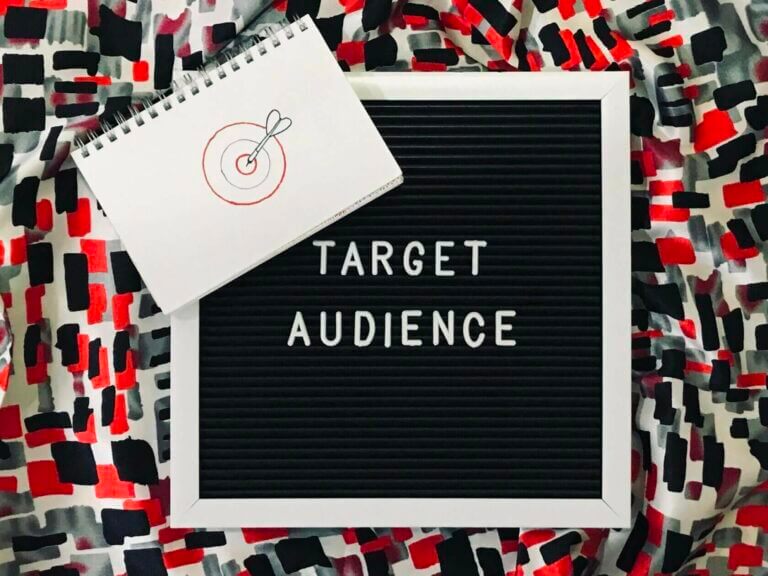 Social media marketing target audience wrote on a boad with a drawing of a target on a pad.