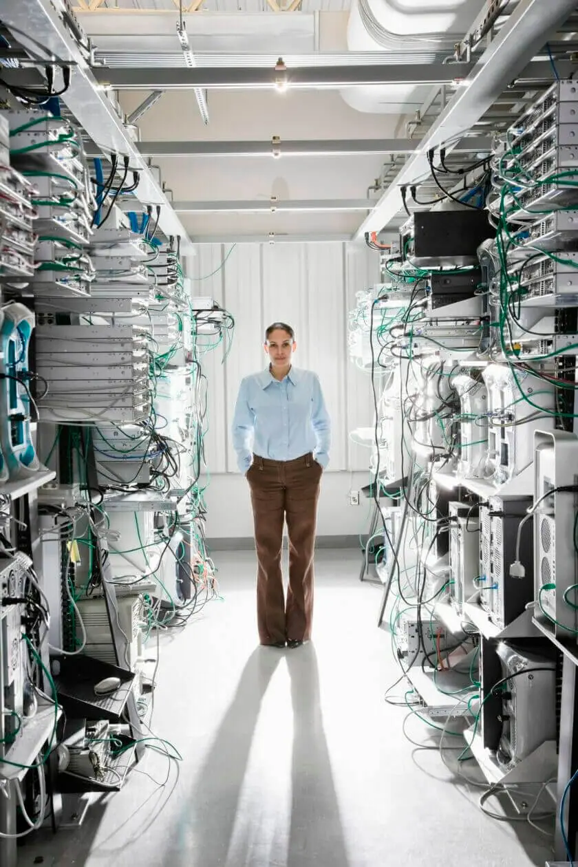 Vietnamese woman technician working in the aisle of a computer server farm.