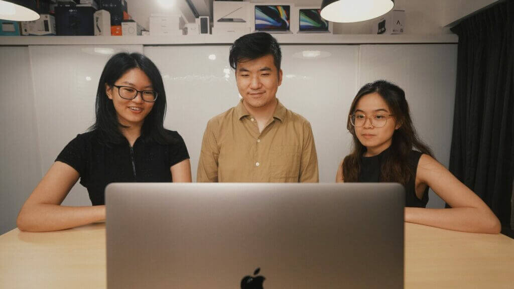 our logo design team at web design saigon smiling at their laptop.