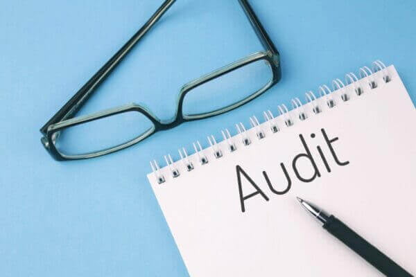 Reading glasses and blank with word PPC AUDIT on a blue background.