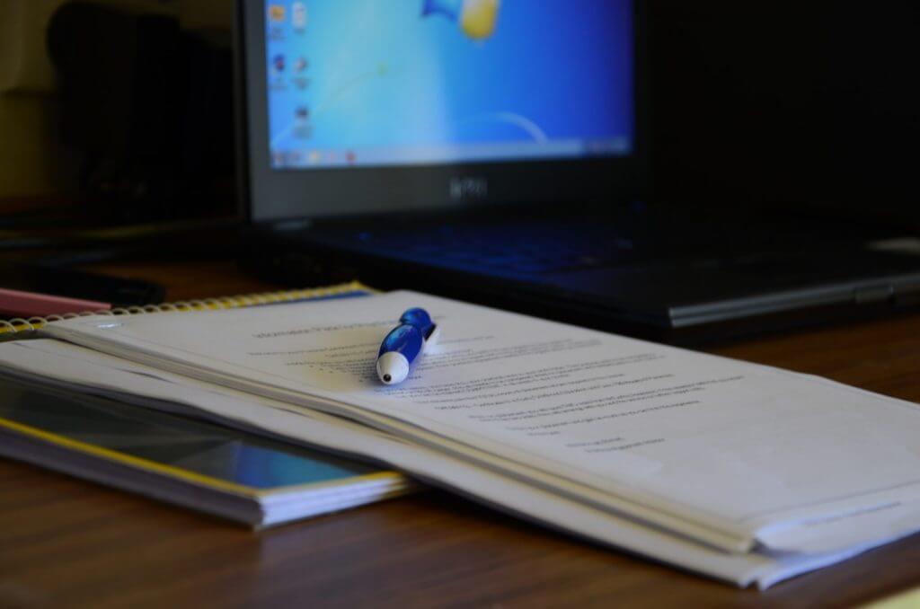 delivering content creation using a pen and paper with computer in background.