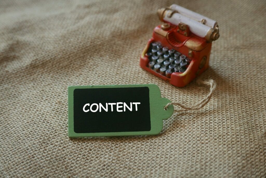 A red miniature of vintage typewriter with wooden tag written with CONTENT.